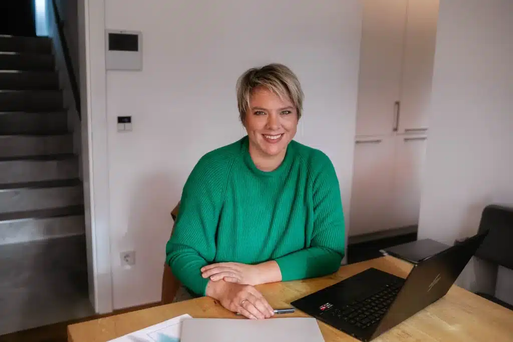 Cornelia sitzt mit einem Lächeln im Büro vor ihrem Planungslaptop.